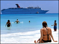 Cruise Groups - People on a white sand beach with a cruiseship in the distance.